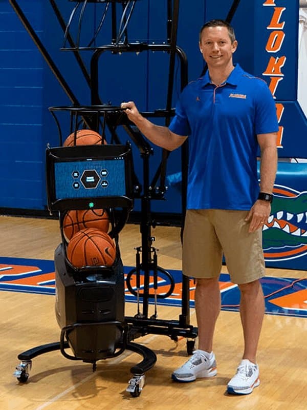Mike White, Head Coach, Florida / Georgia Men's Basketball, alongside a Dr. Dish shooting machine
