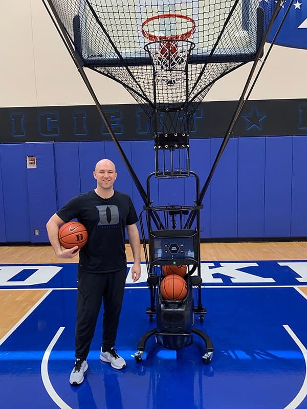 Sam Miller, Associate Head Coach, Duke Men's Basketball, alongside a Dr. Dish shooting machine